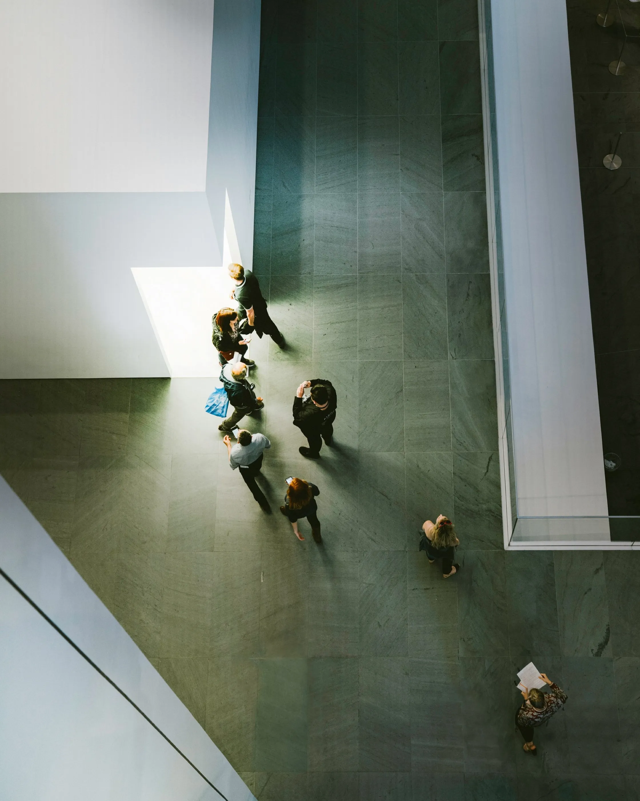 People walking through a light-filled office atrium, seen from above