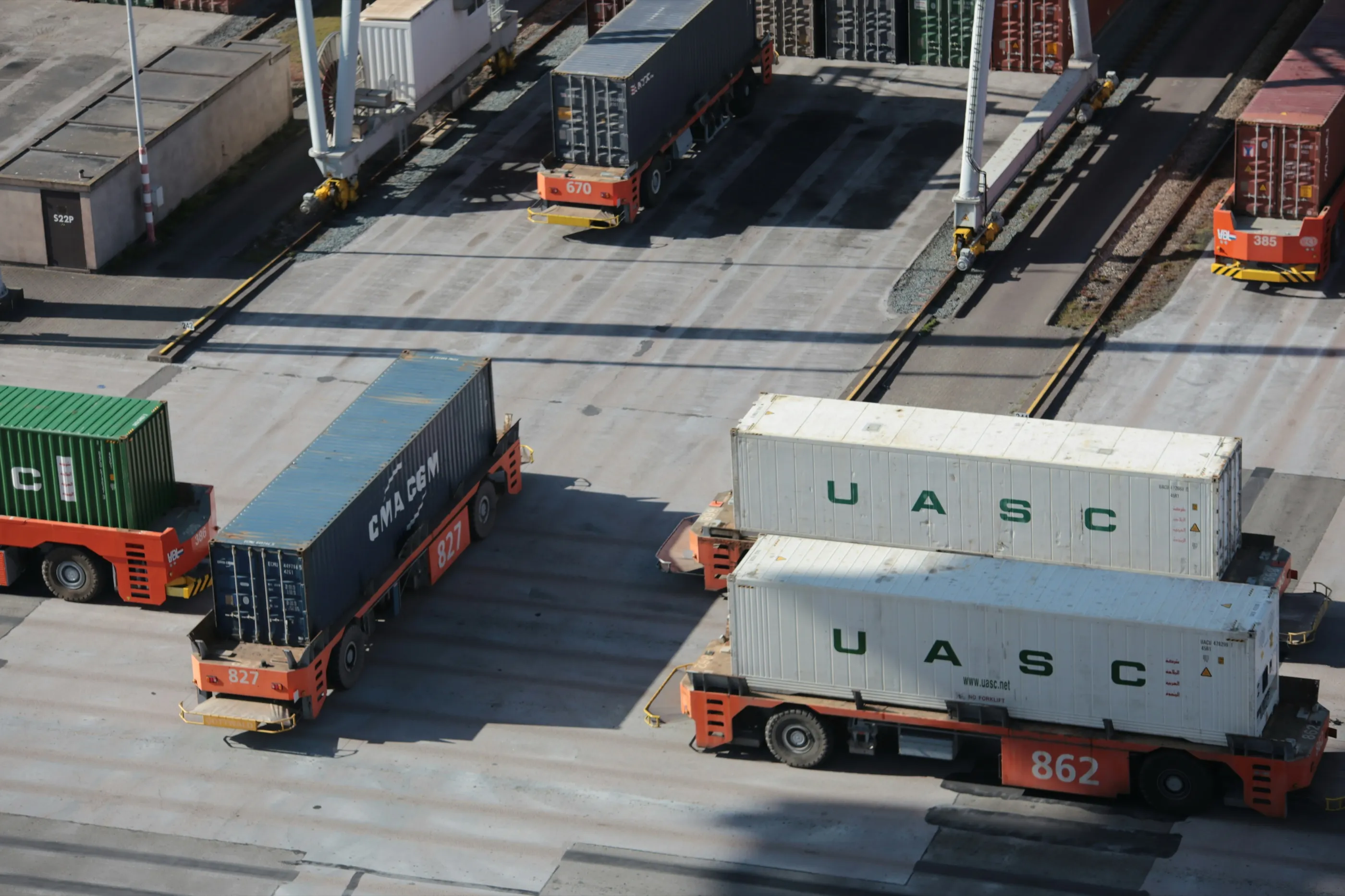 Aerial view of shipping containers being moved across a port